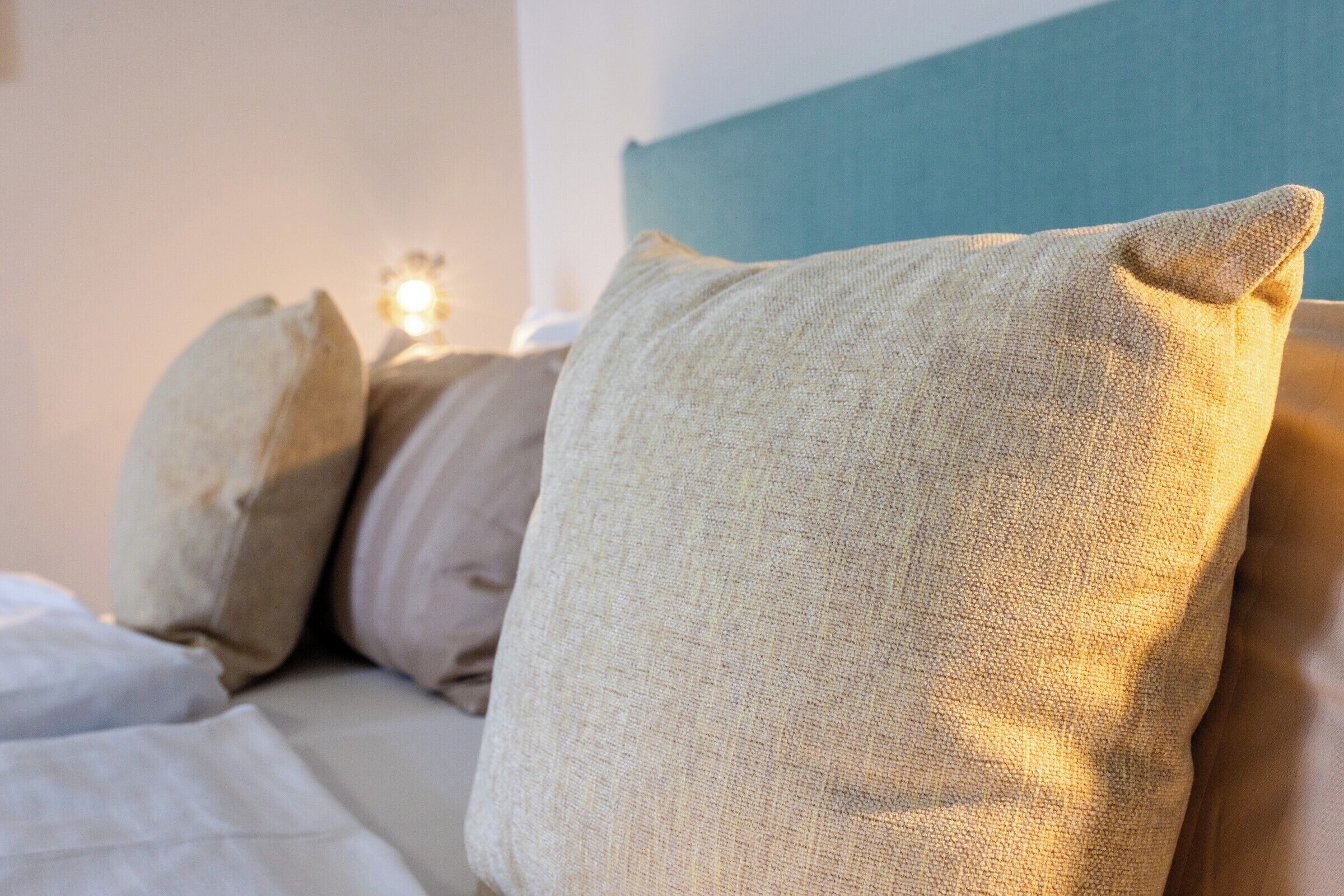 A bed with beige pillows and a blue headboard.