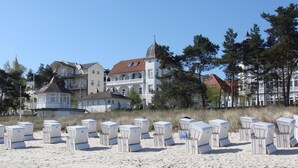 Un hôtel en bord de mer composé de plusieurs bâtiments, dont une tour imposante. Au premier plan, on peut voir des rangées de chaises de plage alignées.