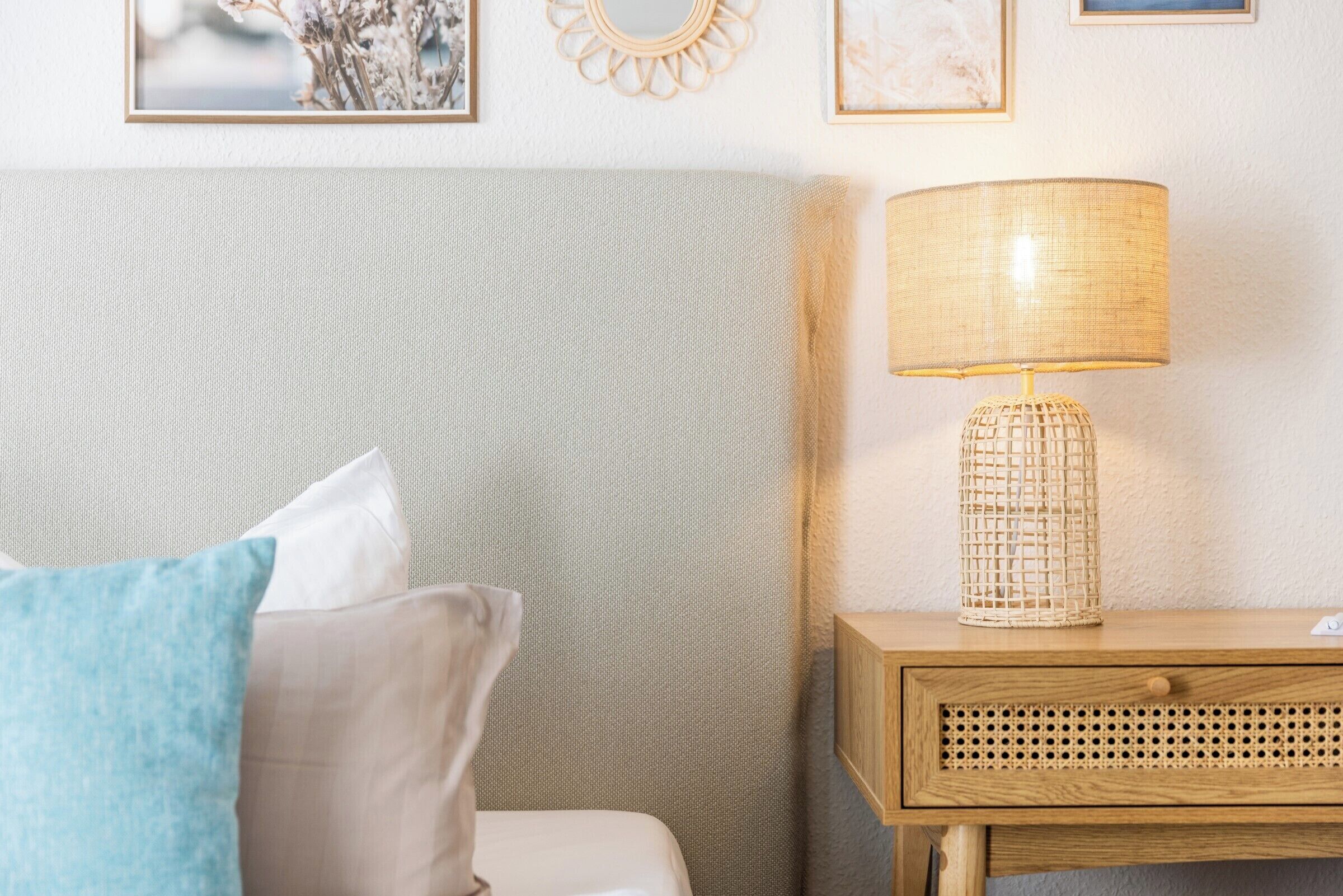 A neatly arranged bedroom with a bed, pillows, a bedside table with a lamp, and wall decor.