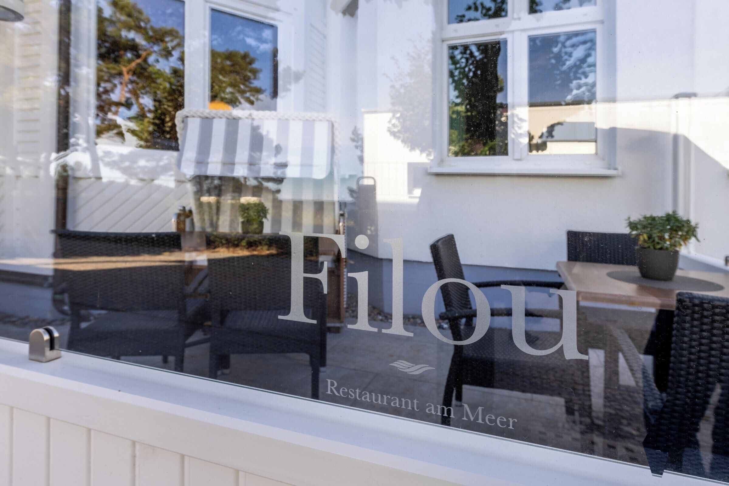 A restaurant window with the name "Filou" and the text "Restaurant am Meer".