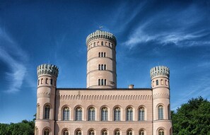 A castle-like building with two towers and a central tower, featuring arched windows and a symmetrical facade.