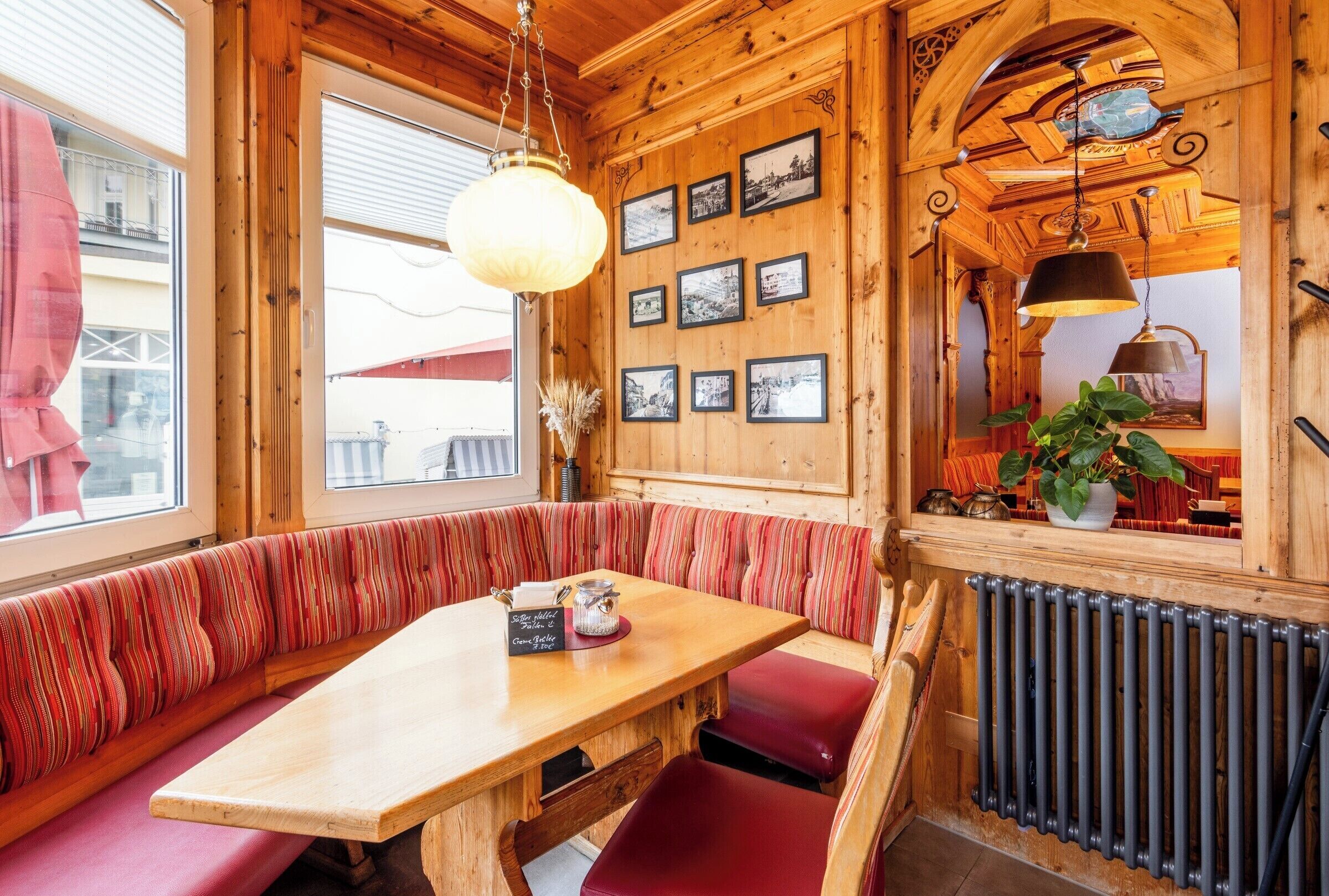 A wooden interior with a bench seating area, a table, and framed pictures on the wall.