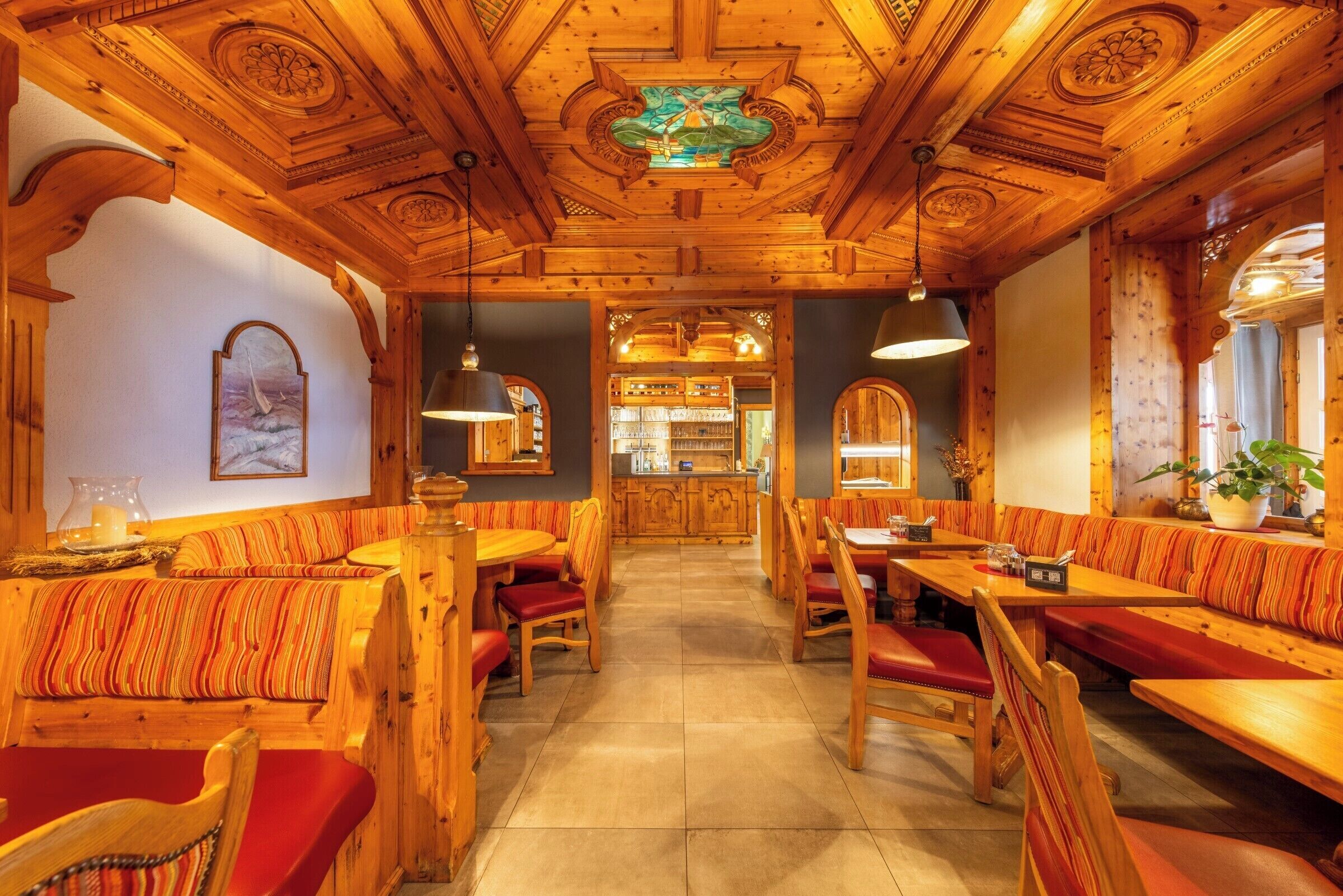 A restaurant with wooden booths and tables, a bar area, and a mural on the wall.