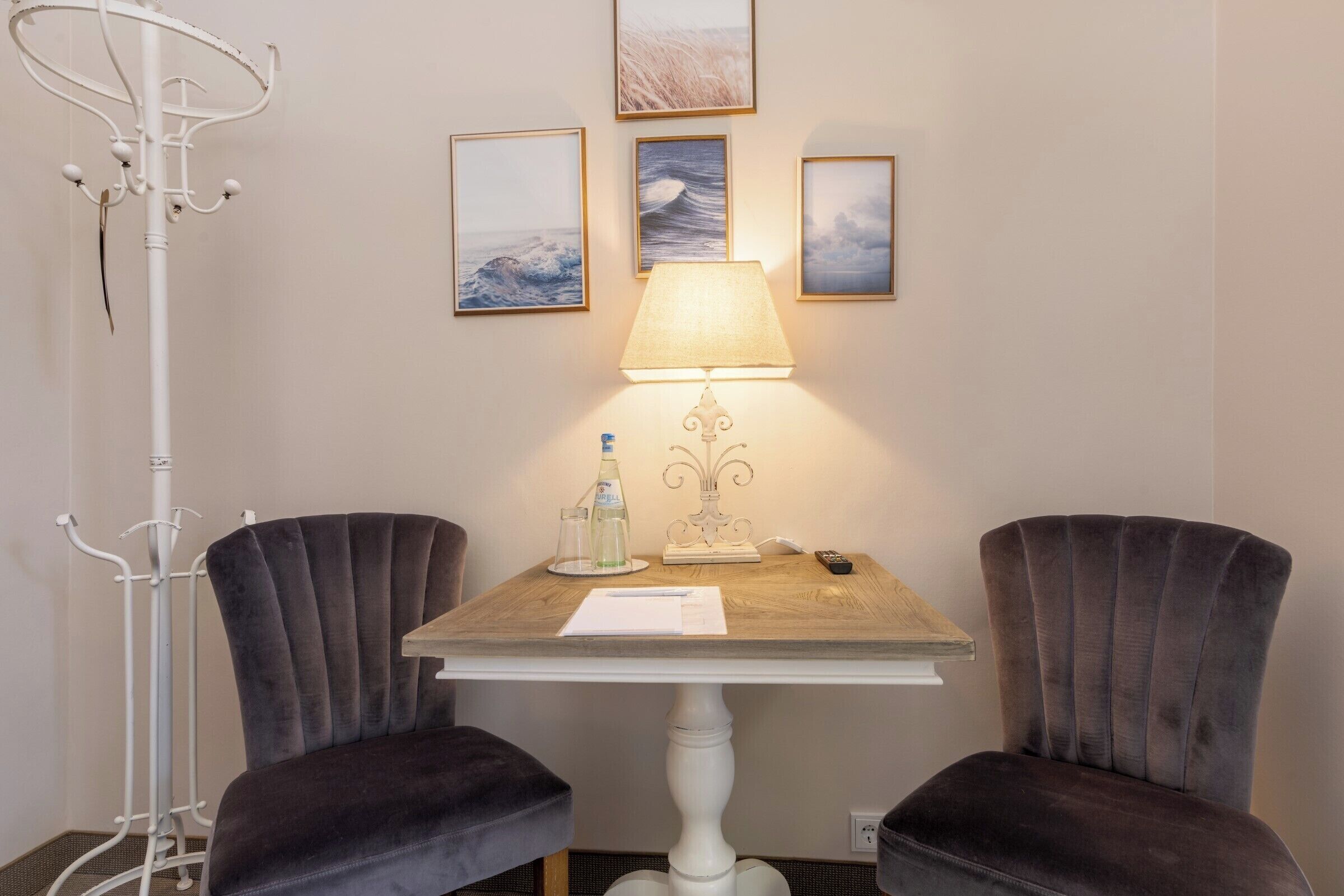 Una habitación con una mesa, dos sillas, una lámpara y decoración en la pared.