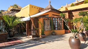 A courtyard with potted plants, a thatched-roof structure, and a large mural of a leopard. - Apartment at 200 meters from the beach! Sea view. And communal pool. (Benalmádena)