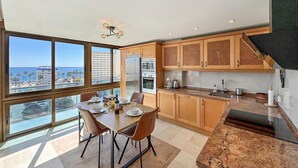 A modern kitchen with wooden cabinets, a granite countertop, and a view of the ocean. - Apartment at 200 meters from the beach! Sea view. And communal pool. (Benalmádena)