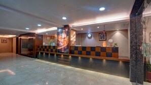 A hotel reception area with a check-in counter, a reception desk, a clock, and a reception sign. - Treebo B&B (Ranchi)