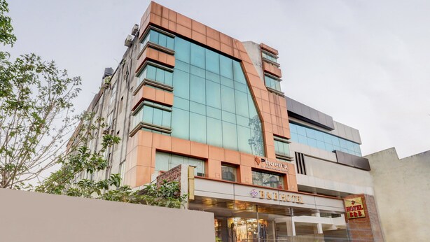 A modern hotel with a glass facade, a B&B sign, and a Phoenix logo. - Treebo B&B (Ranchi)