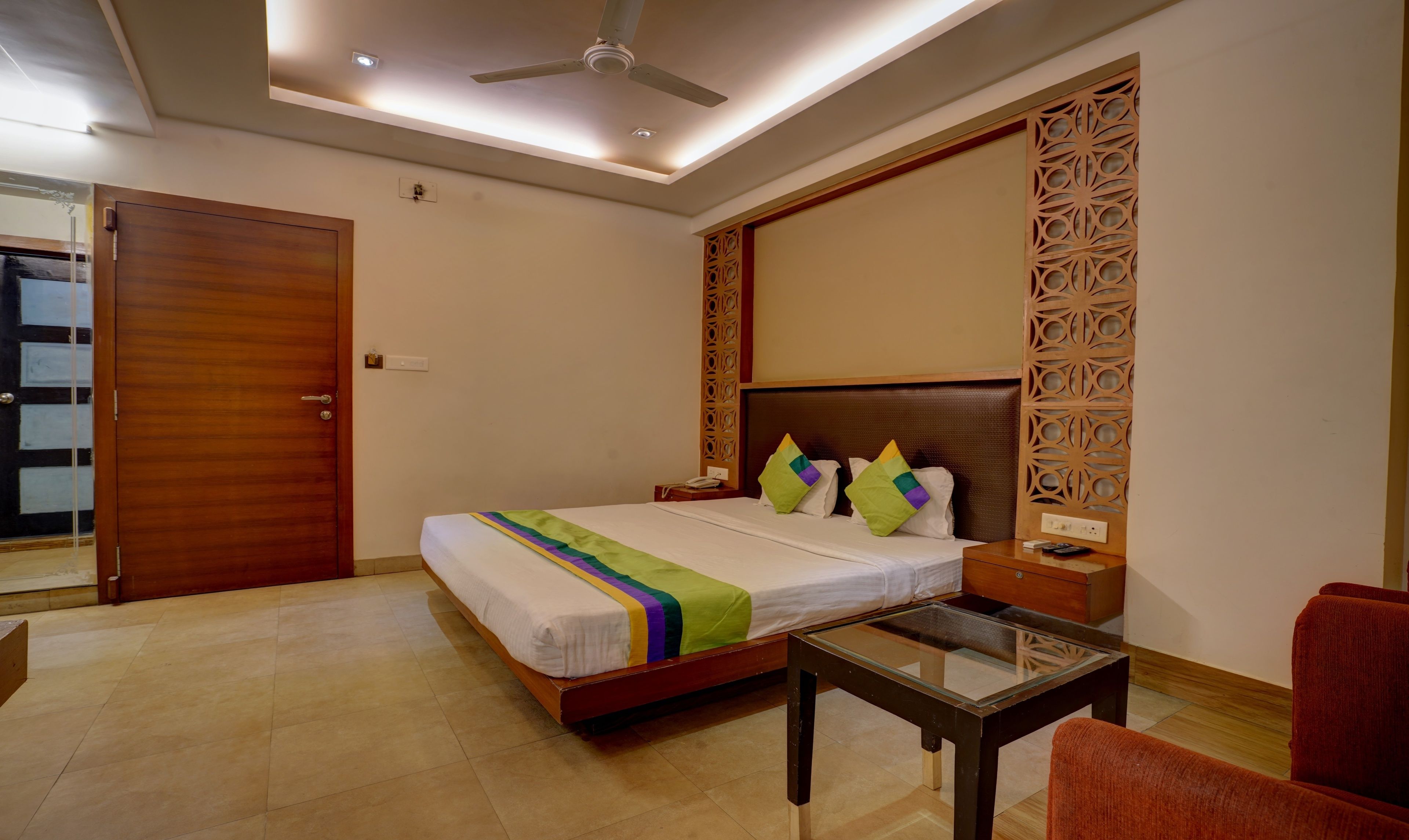 A hotel room with a bed, bedside table, and a glass-top table.