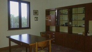 A room with a wooden table, chairs, a cabinet with glass doors, and a window. - Campanedda (SS): Villa 10 'from the sea: app. 1 (Sassari)