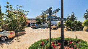 A signpost with directions to various local businesses including a bar, restaurant, and driving range.