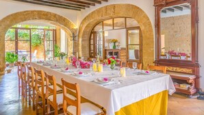 A dining area with a long table set for a meal, arched stone walls, and a large mirror. - Historic Finca in Mallorca with Pool for 8 Guests (Andratx)