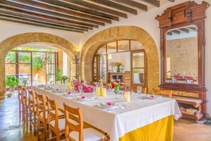 A dining area with a long table set for a meal, arched stone walls, and a large mirror.
