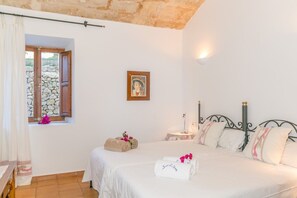 A bedroom with a bed, a nightstand, a wall-mounted picture, and a window with a view of rocks.