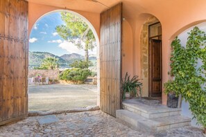 A stone-paved entrance with a wooden door and a view of a mountainous landscape. - Historic Finca in Mallorca with Pool for 8 Guests (Andratx)