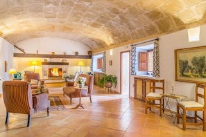 A spacious living area with a stone ceiling, a fireplace, and a view of the outdoors.