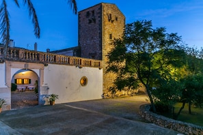 Un bâtiment en pierre doté d’une tour, d’une entrée en arc de cercle et d’une cour pavée.