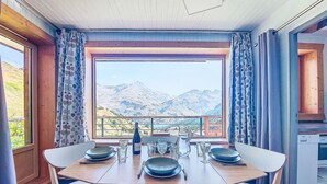 A dining area with a table set for four, a view of mountains, and a wooden ceiling. - Horizon 2000 (Le Lac) by Interhome (Tignes)