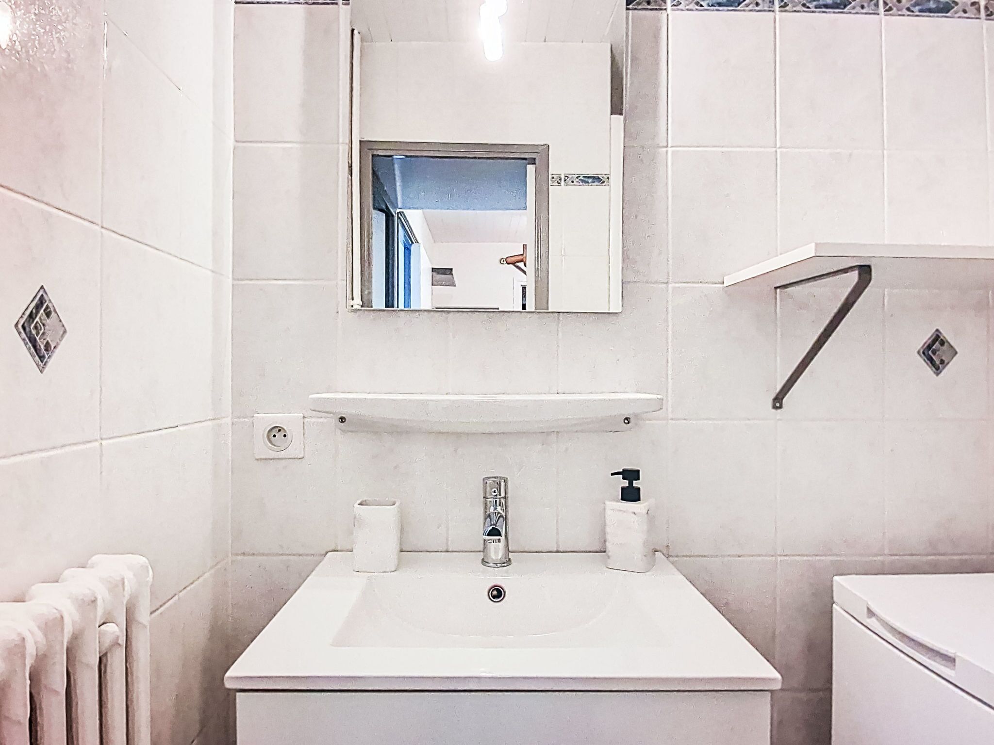 A bathroom with a white sink, a mirror, a towel rack, and a toilet.