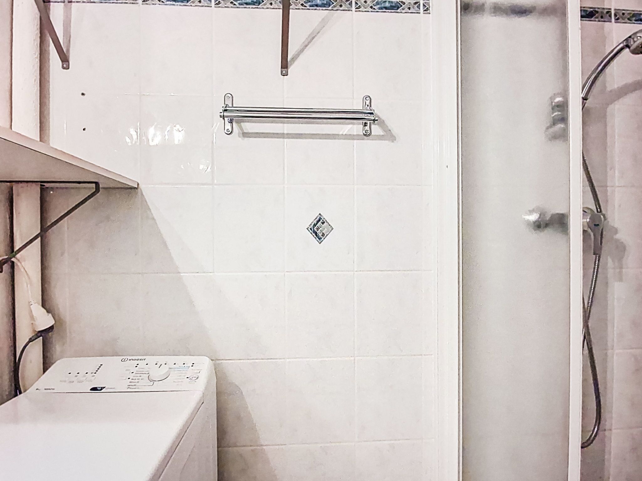 Ein Badezimmer mit Waschmaschine, Handtuchhalter und Duschbereich.