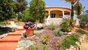 A Mediterranean-style villa with a terracotta-tiled entrance, surrounded by lush greenery and a variety of plants. - Bombilla by Interhome (Moraira)