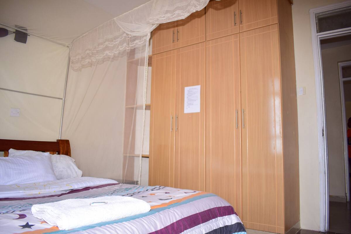 A bedroom with a bed, a wardrobe, and a mosquito net.