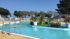 Una piscina con una scala in metallo, circondata da piante in vaso e un recinto bianco.