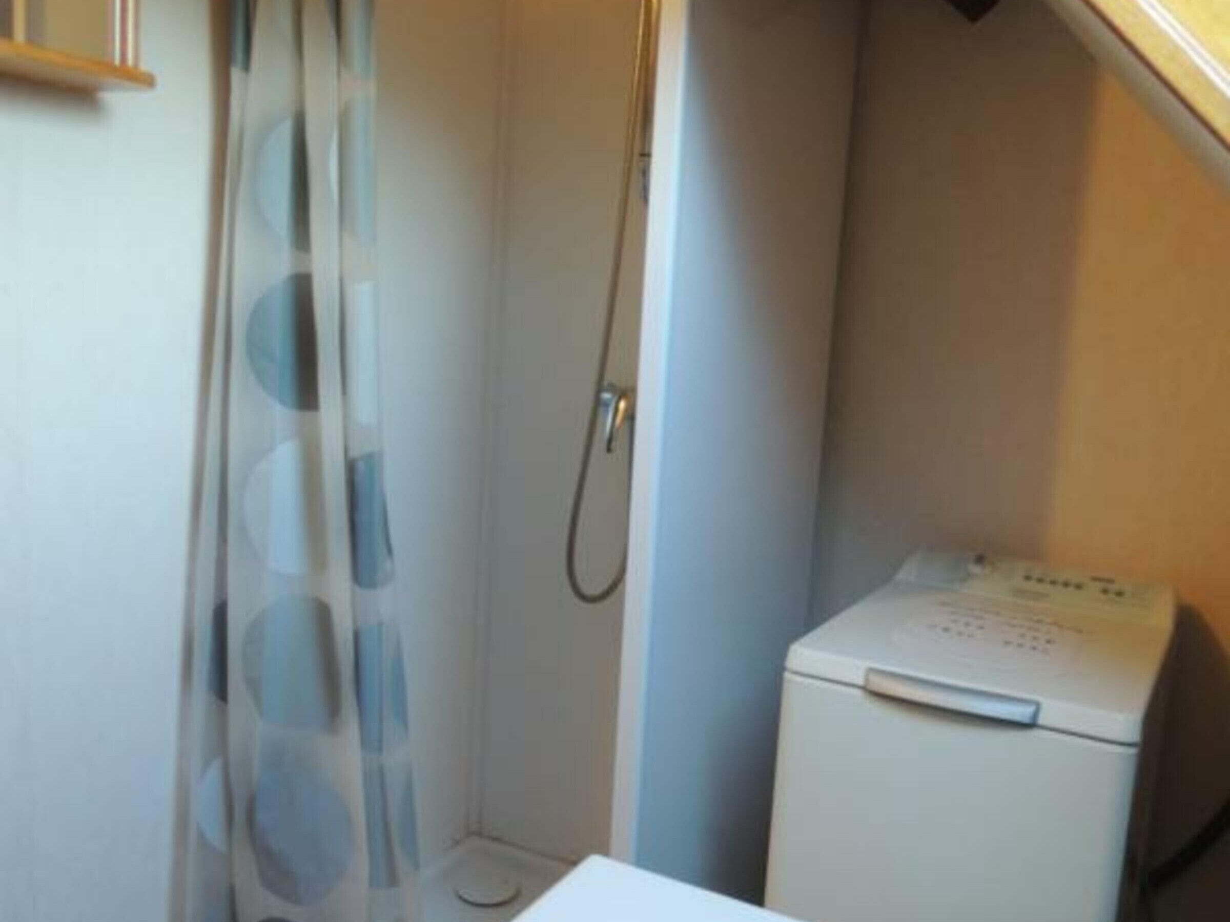 Une petite salle de bain avec une douche, des toilettes et un lave-linge.