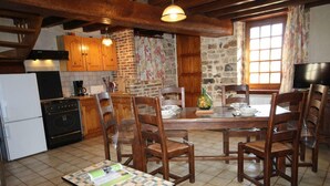 A rustic kitchen with wooden cabinets, a brick wall, and a dining table set for four.
