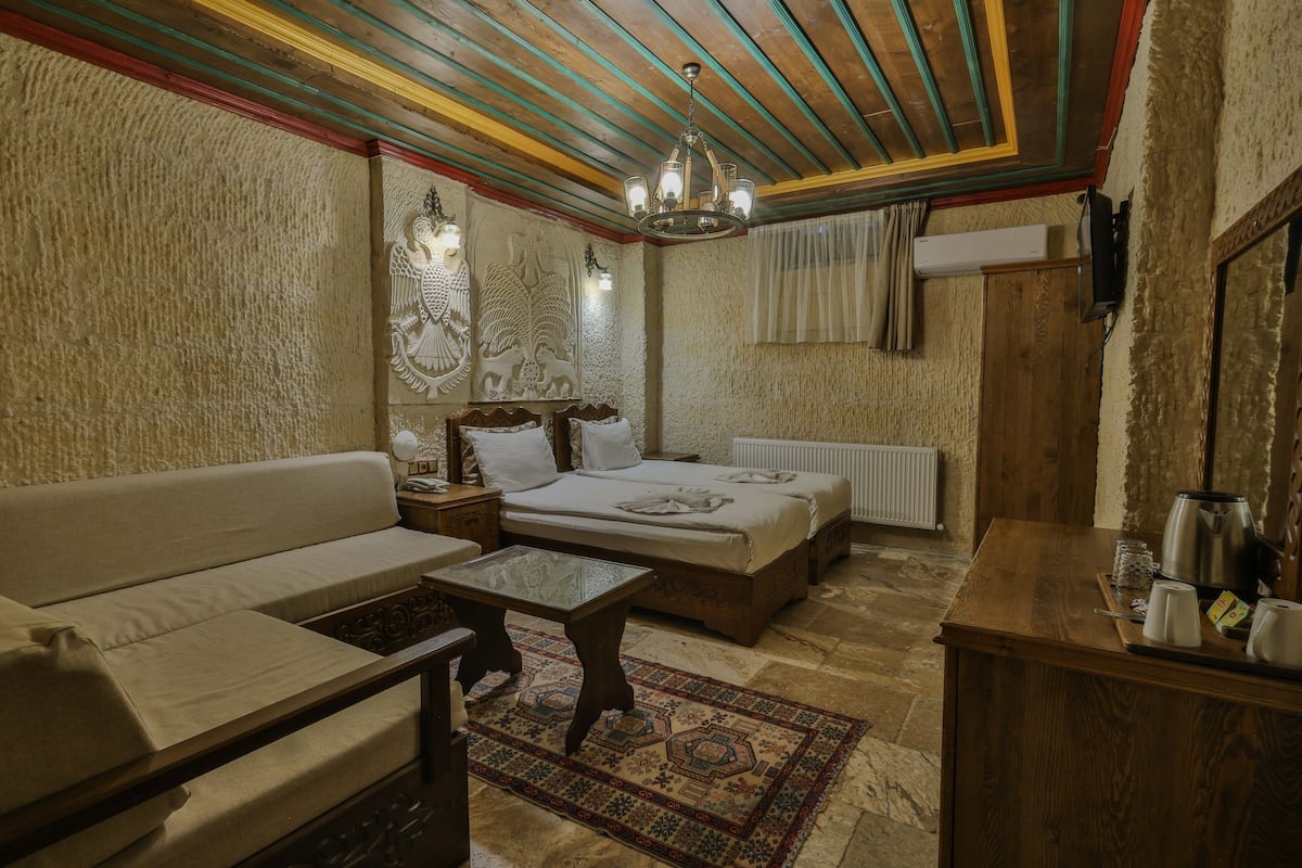 Una habitación acogedora con sofá, dos camas, una mesa de centro de madera y una alfombra estampada.