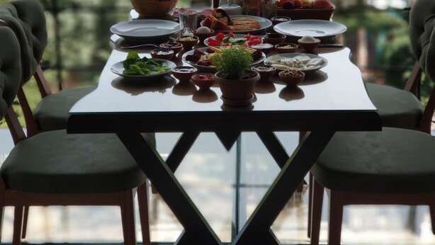 A dining table set for four with plates, bowls, and a small potted plant. - Feel Cappadocia Stone House (Nevsehir)