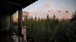 A balcony with a view of a forest and hot air balloons in the distance. - Feel Cappadocia Stone House (Nevsehir)