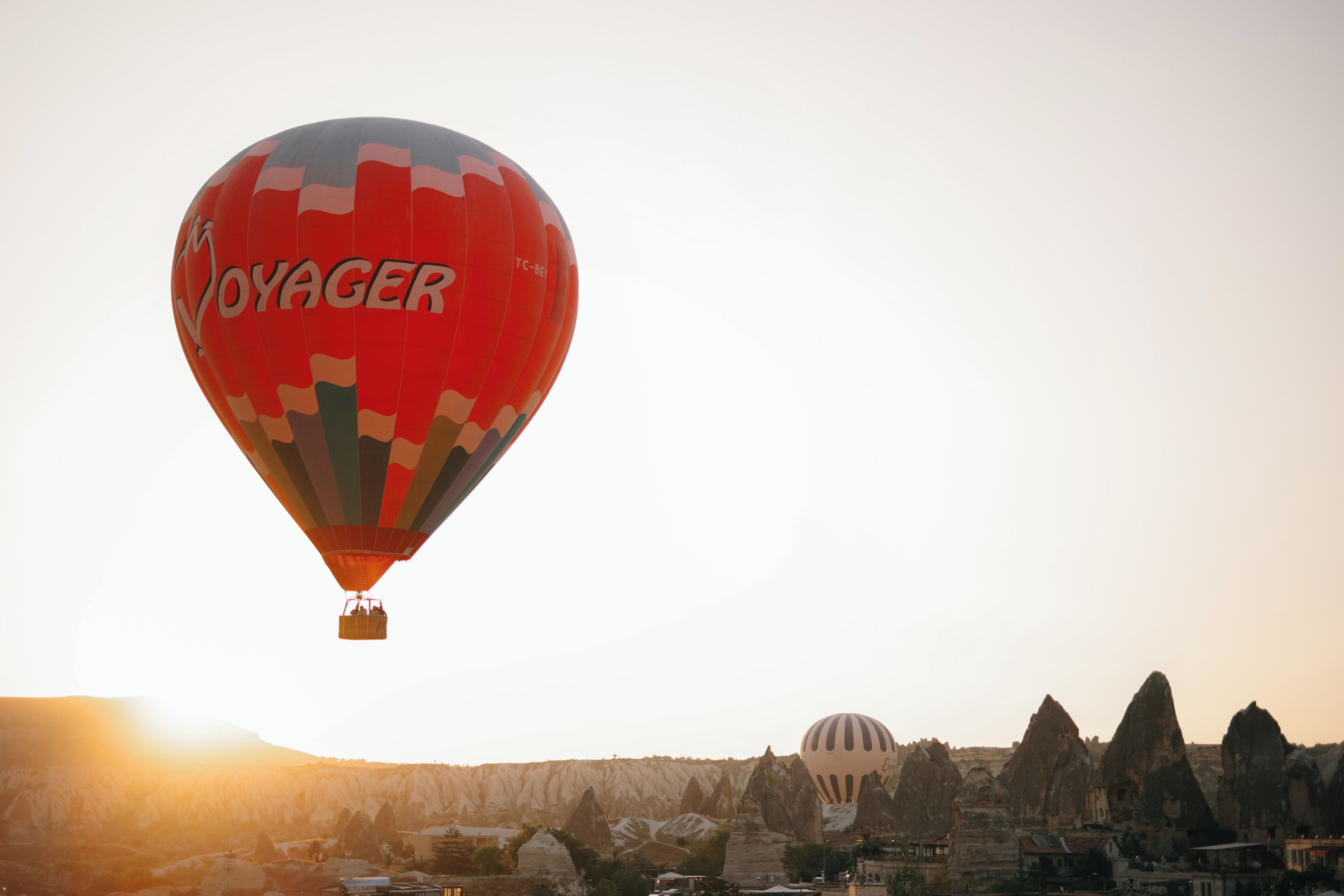 A hot air balloon with the word "VOYAGER" over a landscape with distinctive rock formations and a dome-shaped building.