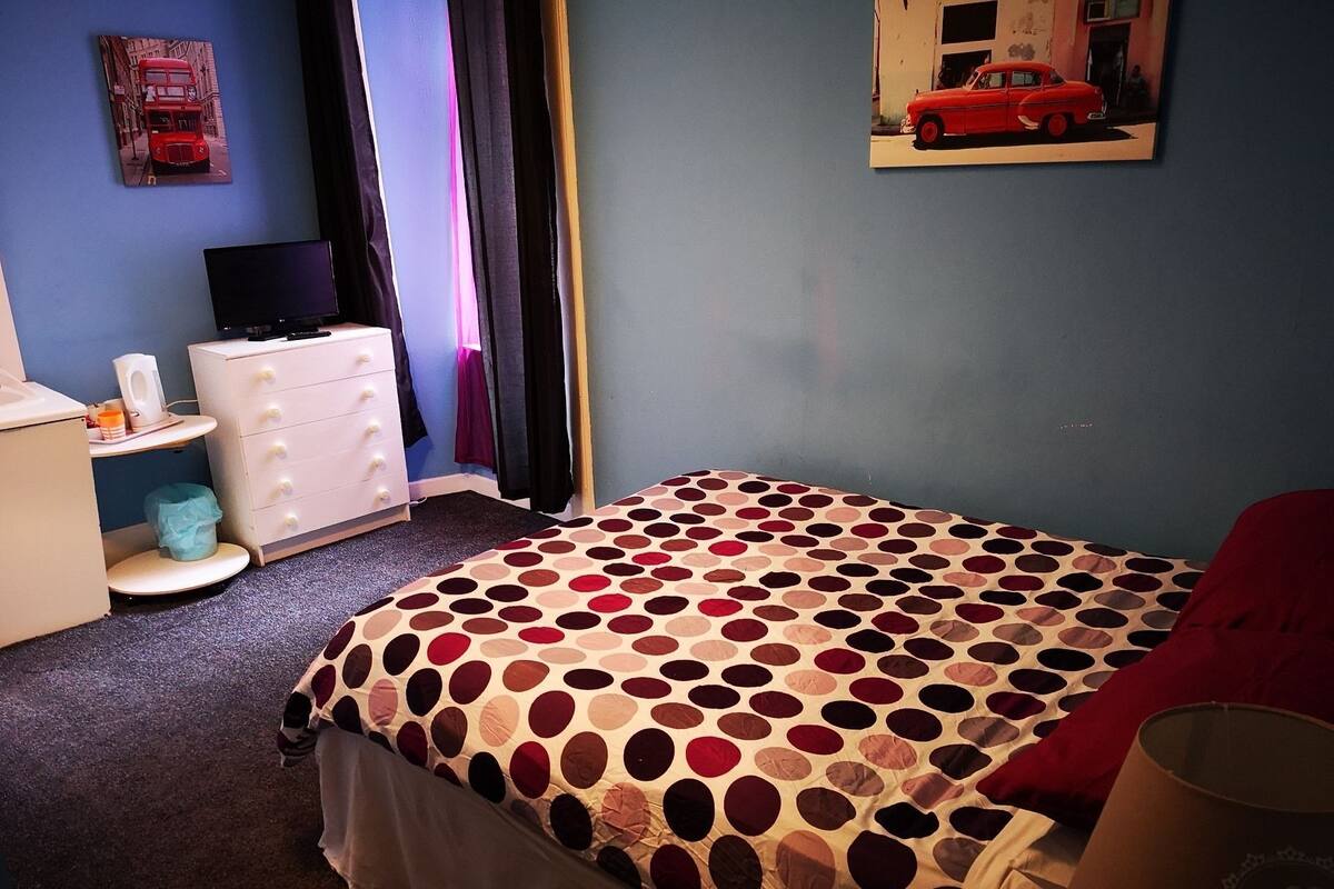 A bedroom with a bed, a dresser, a television, and a poster on the wall.