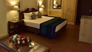 A hotel room with a bed, bedside lamps, a mirror, a dresser, and a floral arrangement on a table. - Adb Rooms The Oak Tree House (Shimla)