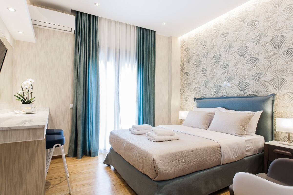 Una habitación de hotel moderna con una cama, una mesita de noche y un escritorio con una silla.