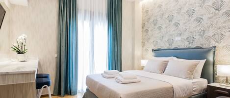 A modern hotel room with a bed, bedside table, and a desk with a chair.