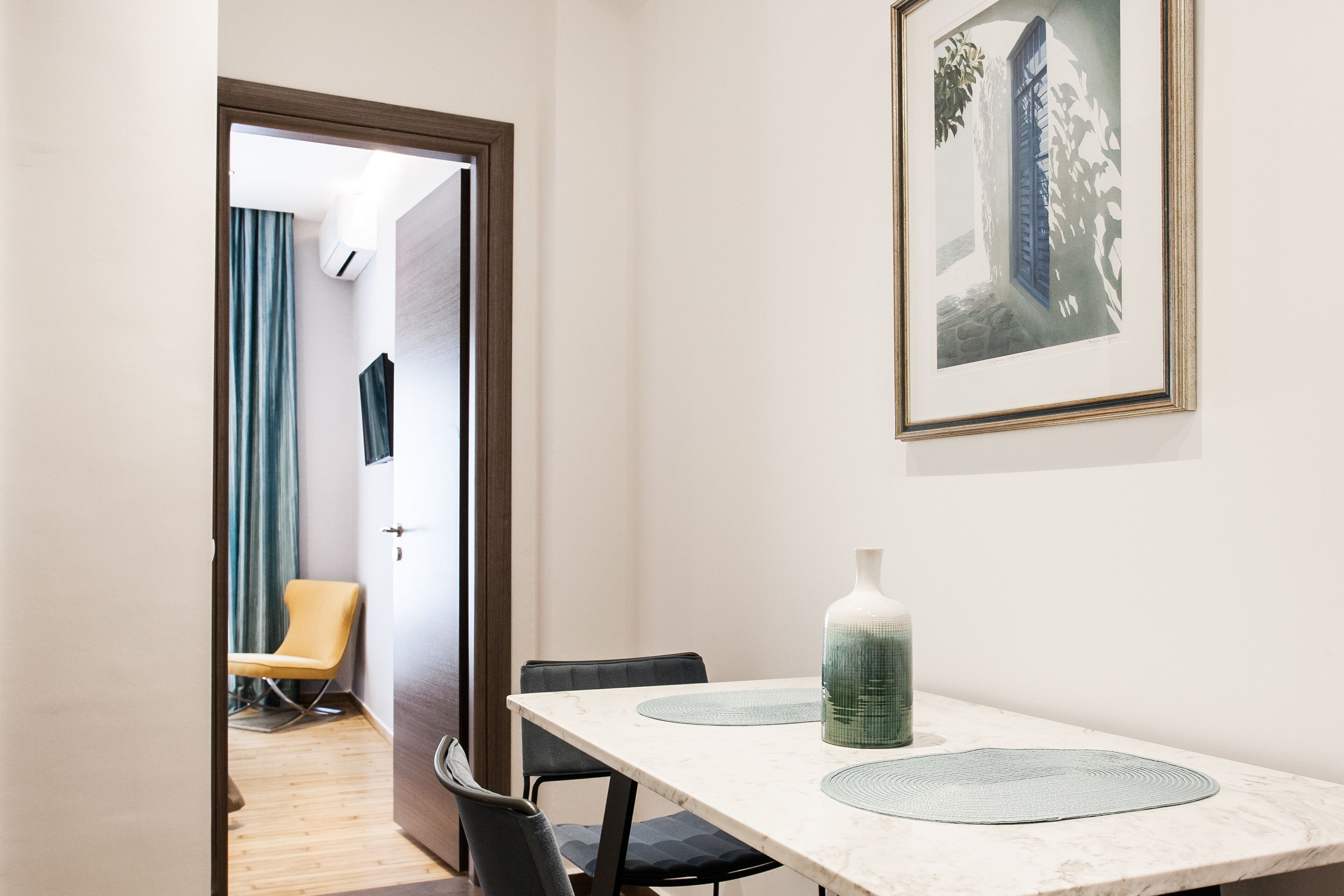 Une pièce comprenant une table à manger, des chaises, un vase et un tableau encadré accroché au mur.