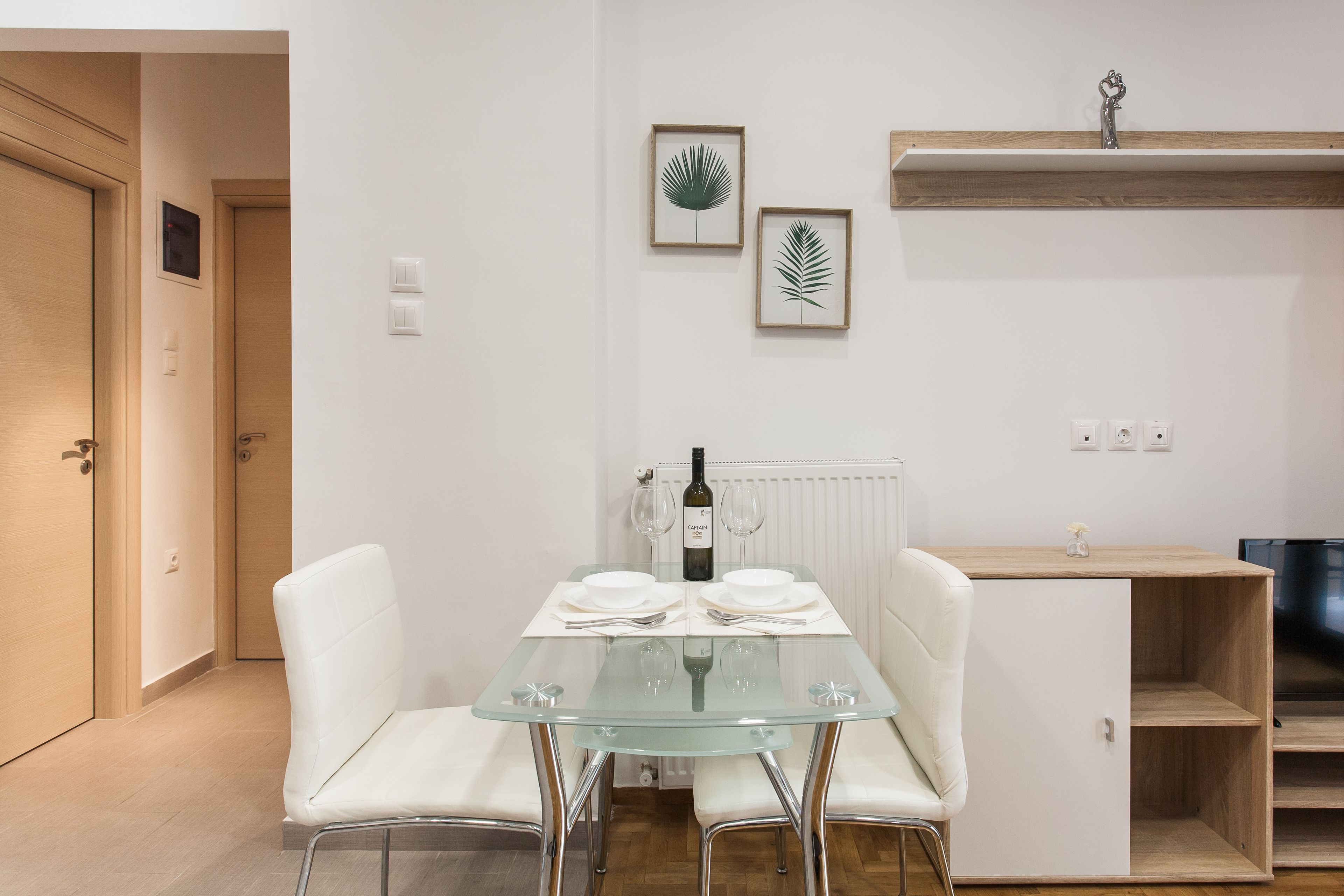 Una cocina moderna con una mesa de vidrio, sillas blancas y una botella de vino.