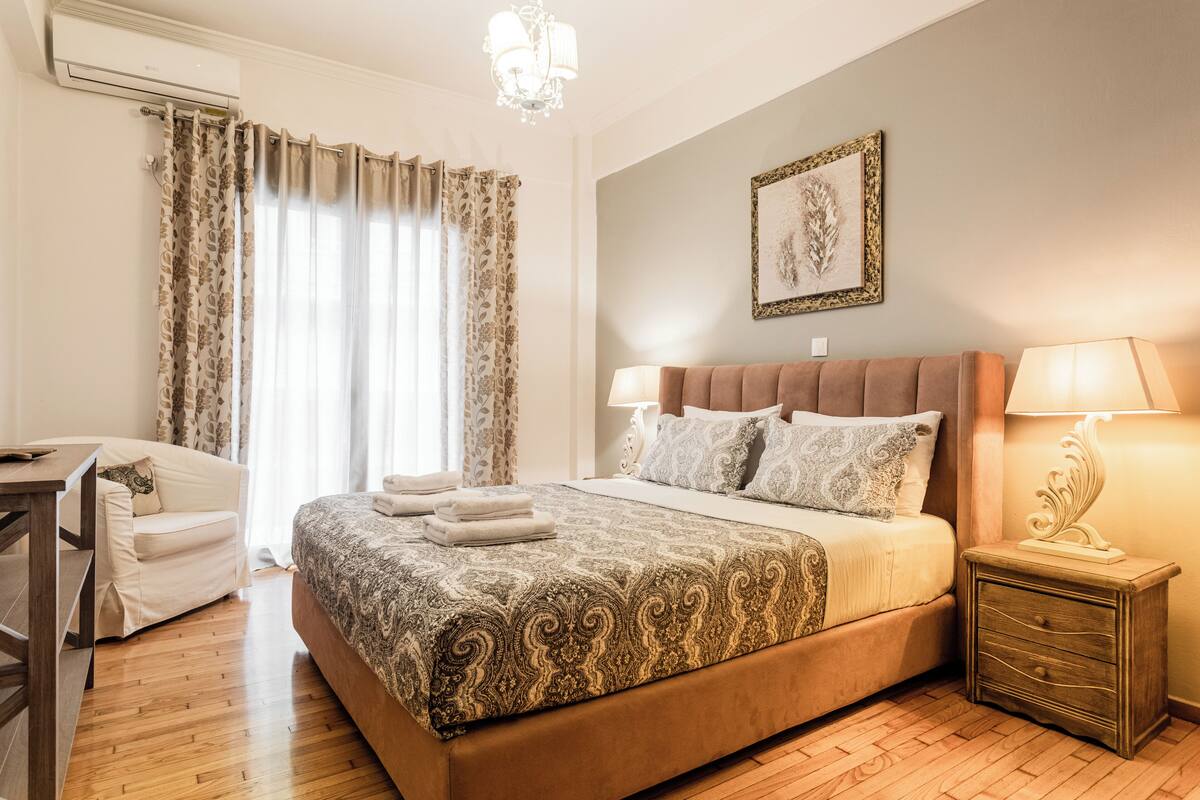 Un dormitorio con una cama grande, un escritorio, una silla y una mesita de noche con lámpara.