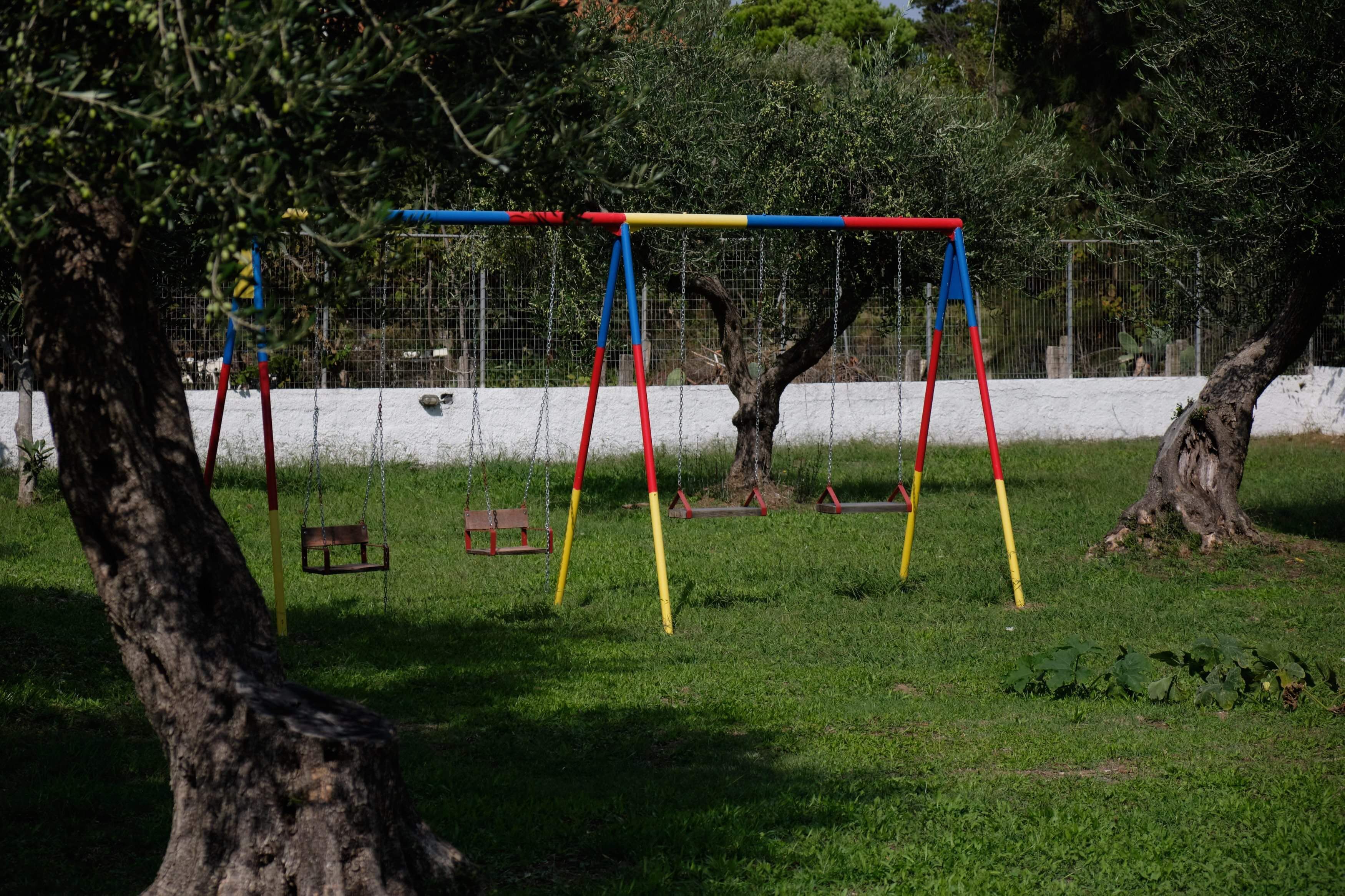Une aire de jeux avec des balançoires et un espace délimité par une clôture.