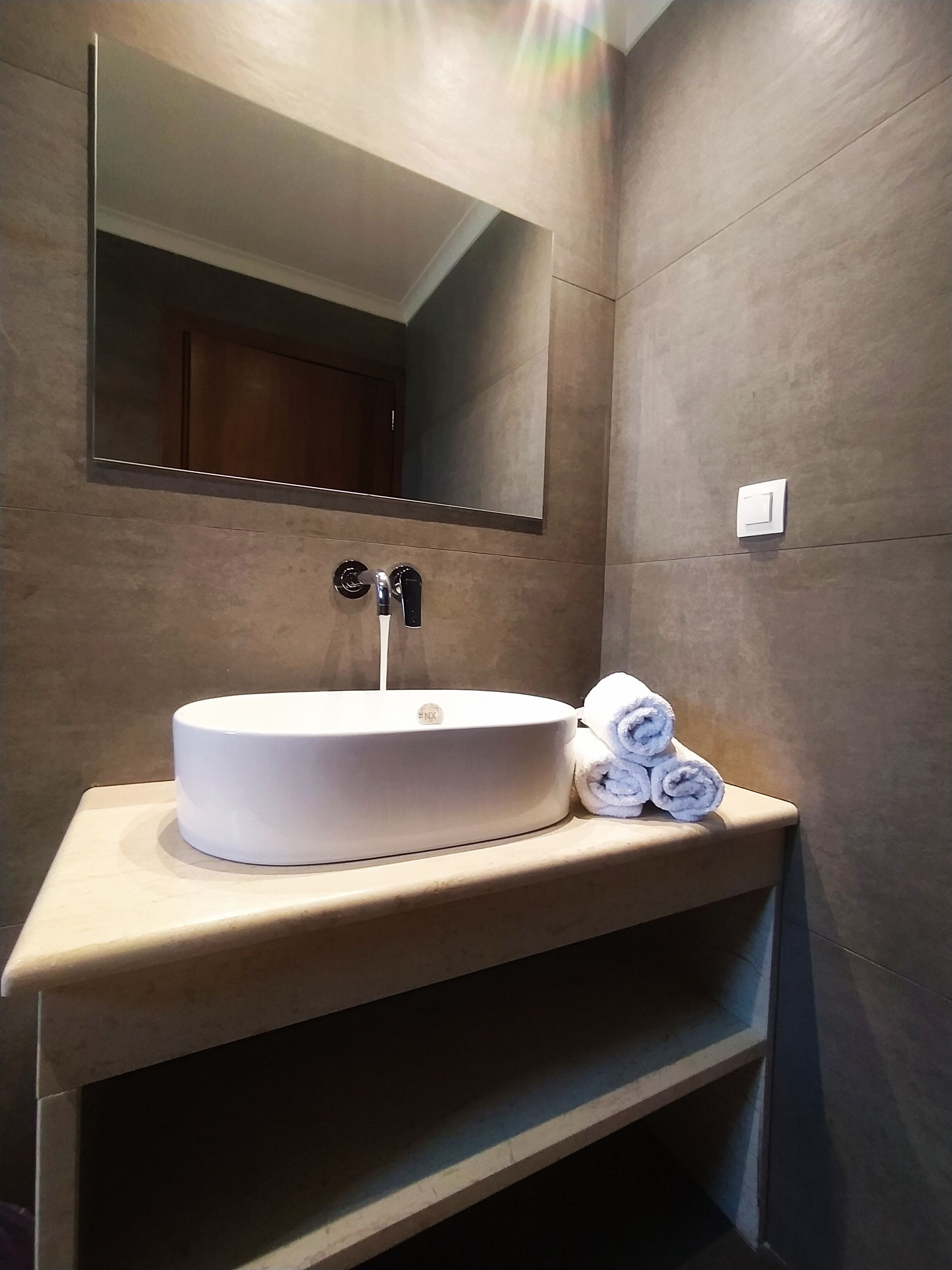 Un bagno con lavandino bianco, specchio e portasciuga.