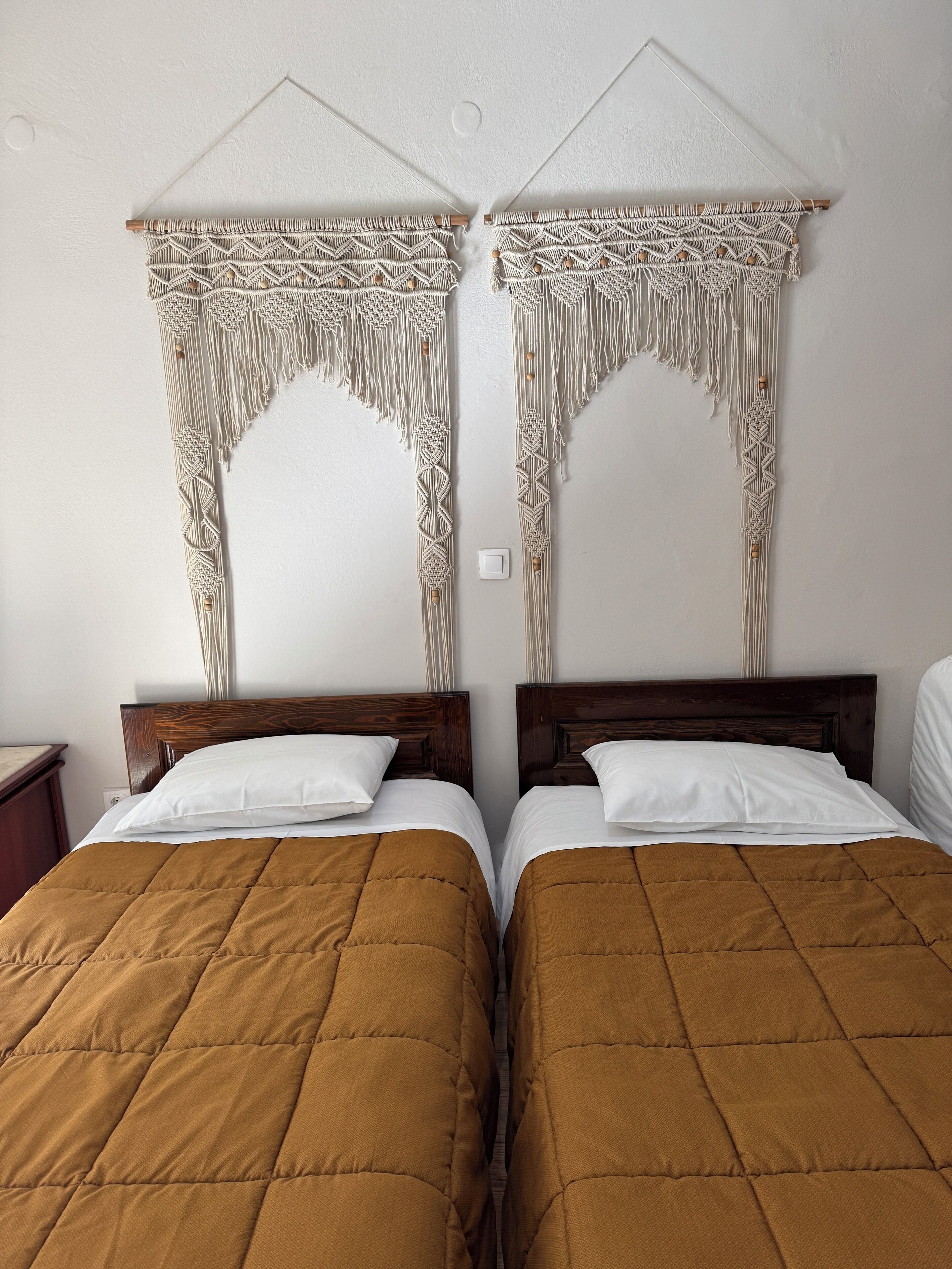 Ein Zimmer mit zwei Betten, jeweils mit Holz Kopfteilen und brauner Bettwäsche.