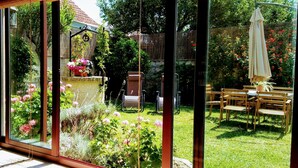 A garden with a stone wall, potted plants, and a wooden table with chairs. - Beautiful house with porch and garden 5' drive from the beach and the mountains. (Moaña)