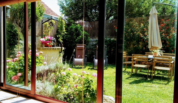 A garden with a stone wall, potted plants, and a wooden table with chairs.