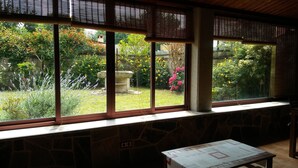 A room with large windows overlooking a garden. There is a stone bench and a table with a placemat. - Beautiful house with porch and garden 5' drive from the beach and the mountains. (Moaña)