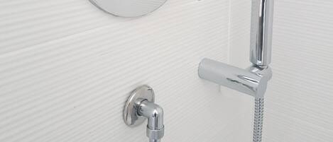 A modern bathroom with a wall-mounted shower control panel, a handheld showerhead, and a flexible hose.