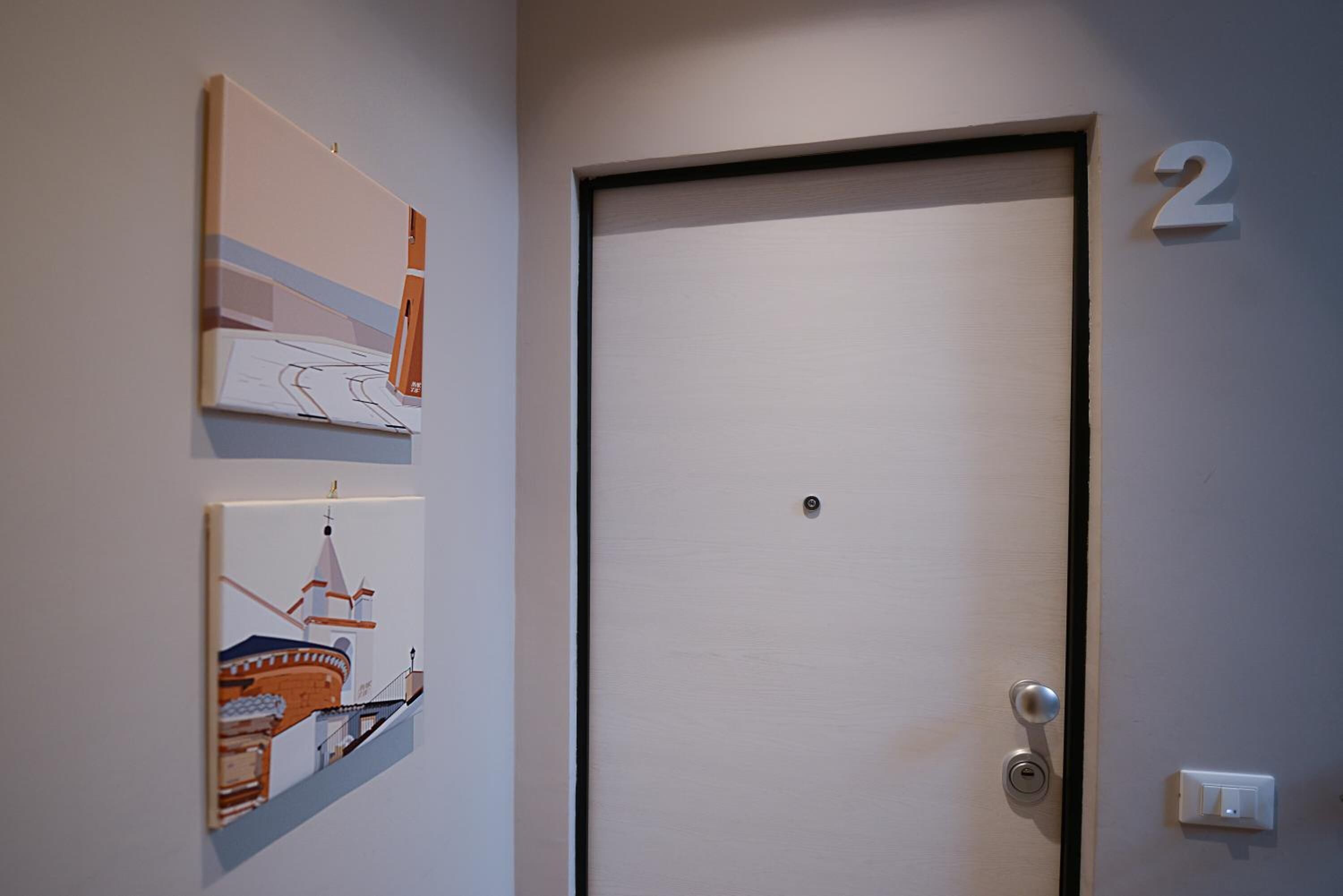 A door with a keyhole and a lock, a number '2' on the wall, and two framed artworks on the wall.