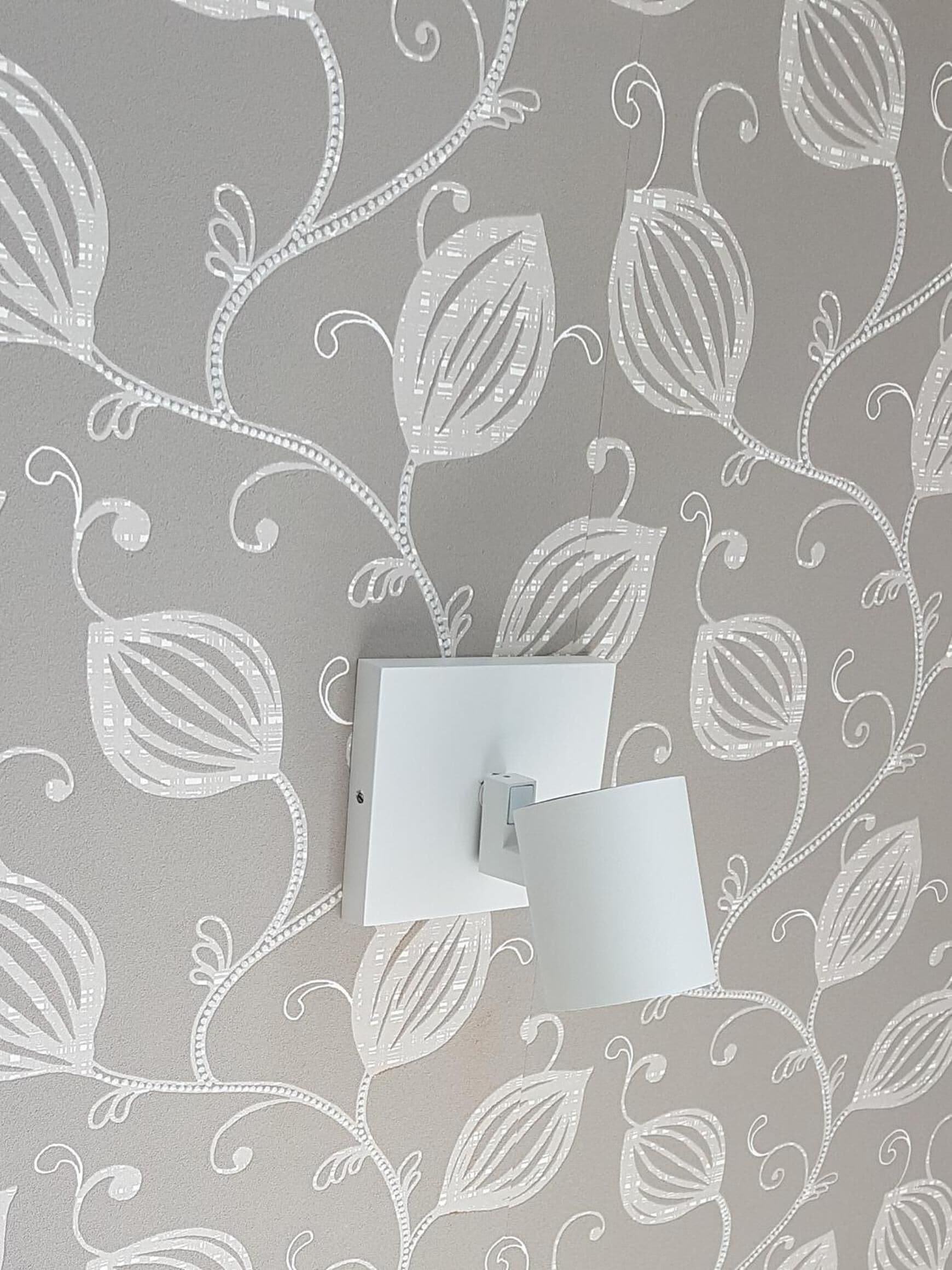 A wall with a leaf pattern and a light switch.
