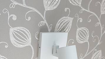 A wall with a leaf pattern and a light switch.